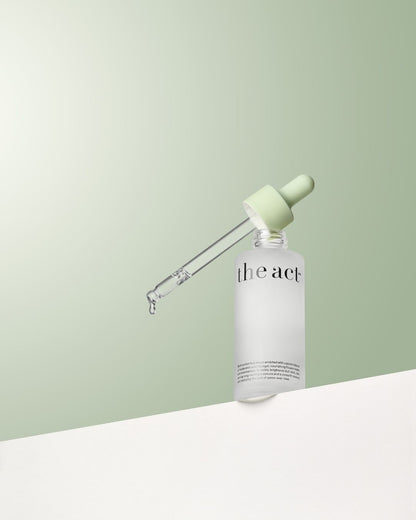 Skincare bottle with dropper labeled 'the act' on a light green background