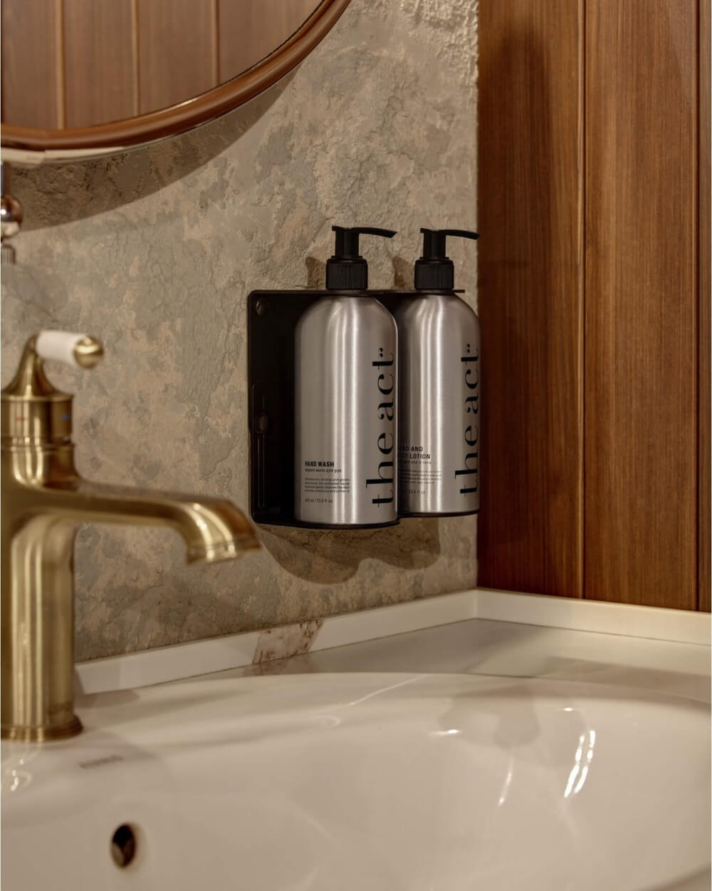 The Act hand wash and hand and body lotion aluminium bottles mounted in a wall bracket in a hotel bathroom